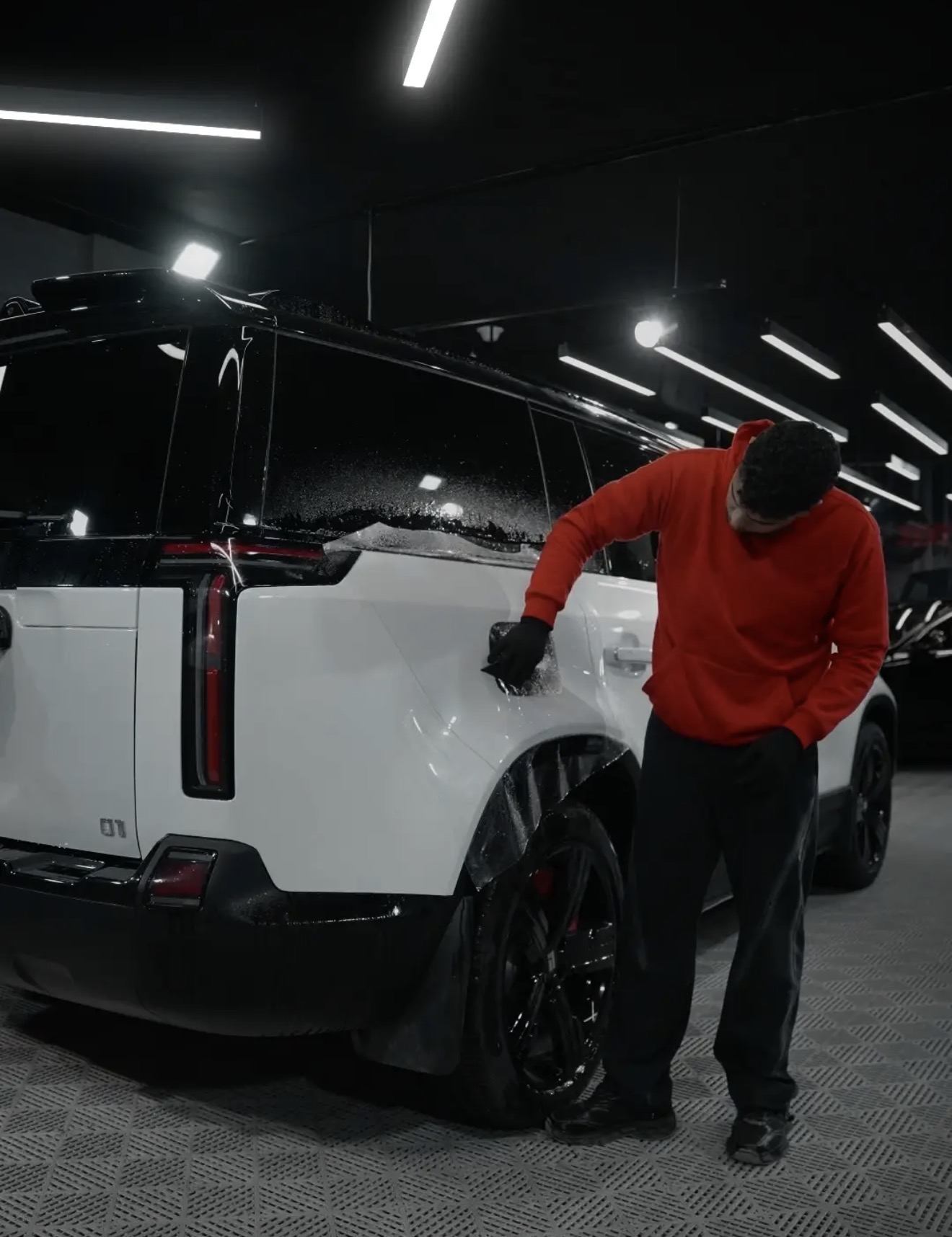 Squeegeeing protection film on a white Rivian SUV